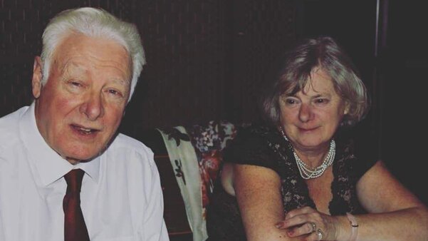 Two people sitting at a table. They are both wearing formal clothing.